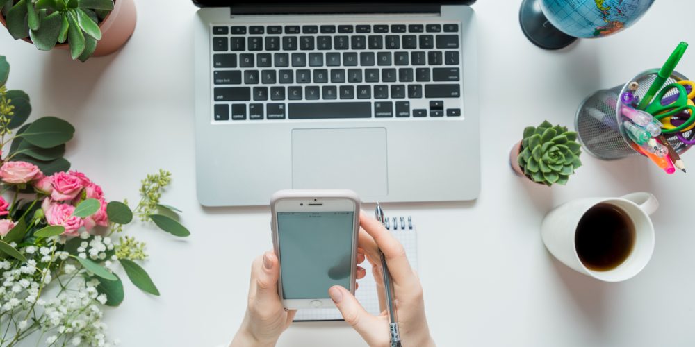 crop-hands-using-smartphone-near-laptop